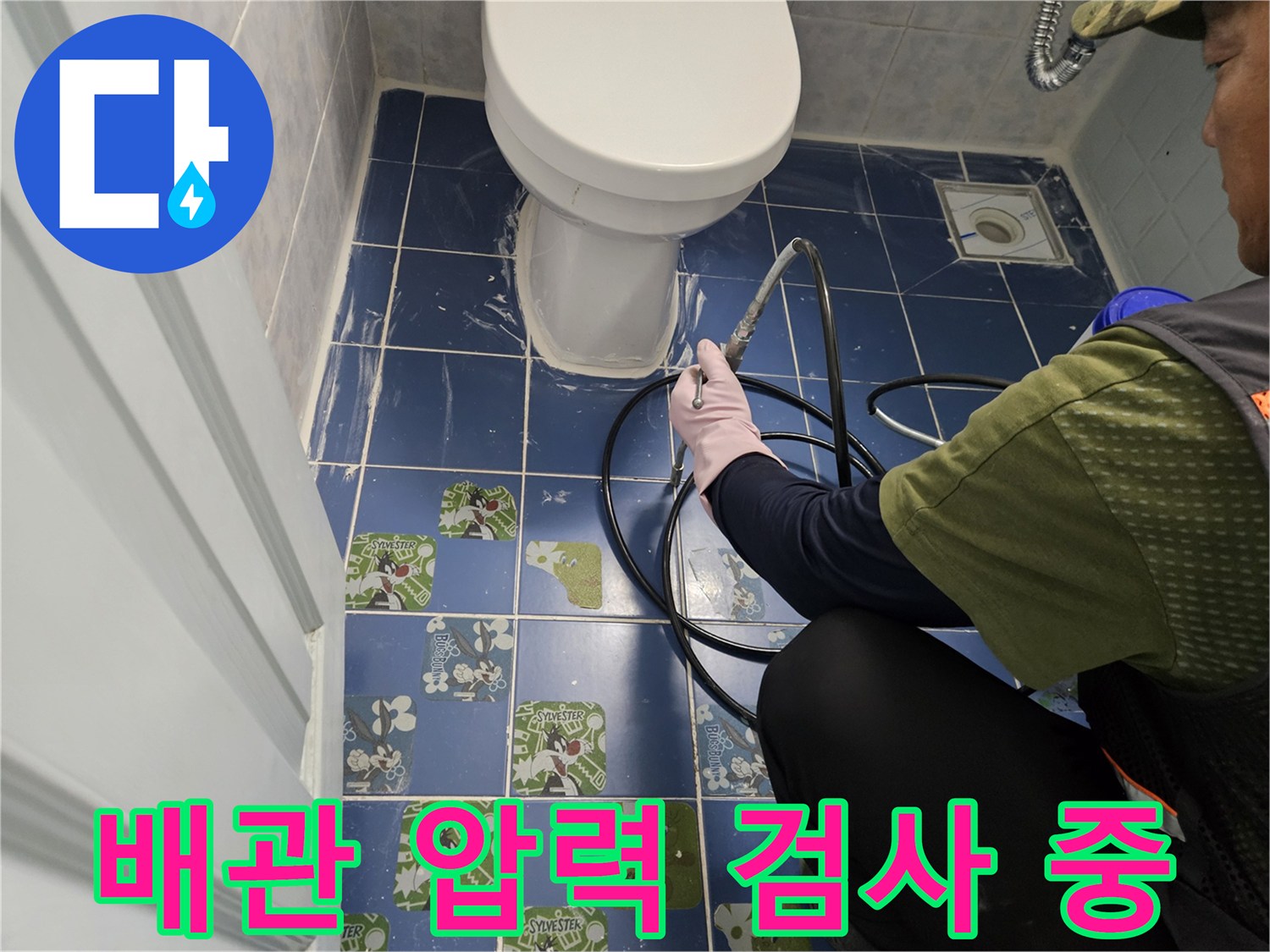 화장실 변기 근처 배관에 연결된 공압 테스트 장비와 호스