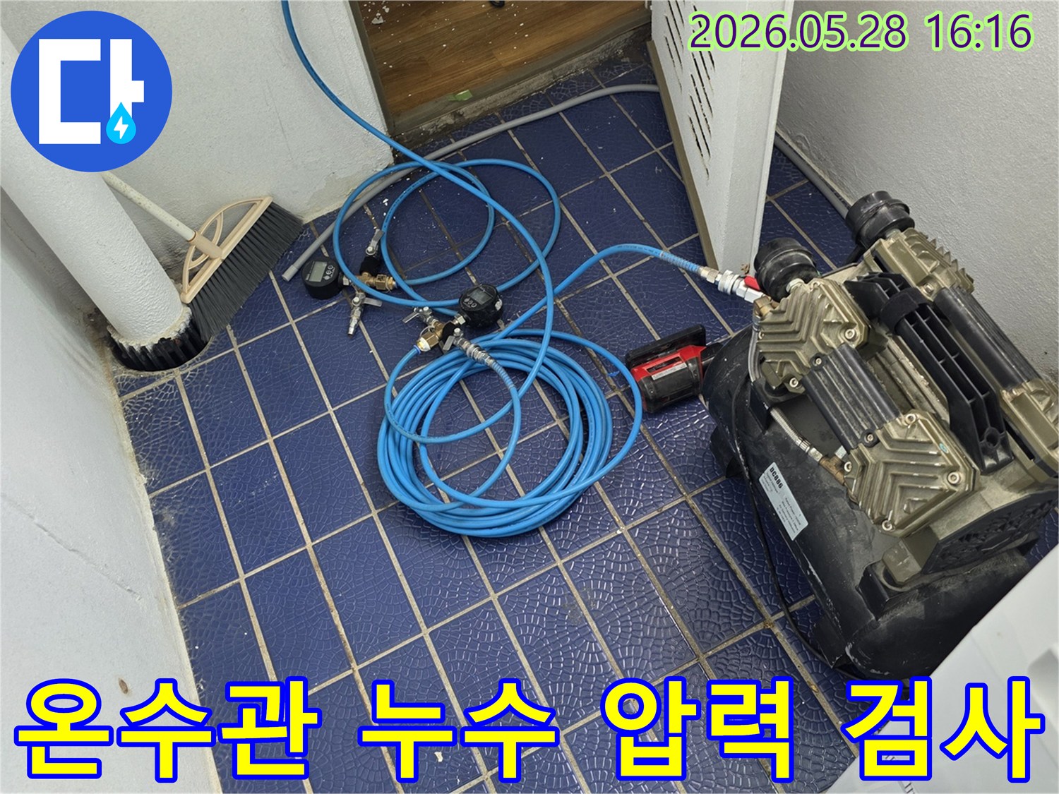 온수관-누수-원인을-찾기-위해-배관에-연결된-공압-장비와-압력-게이지-그리고-파란색-호스가-보이는-작업-현장