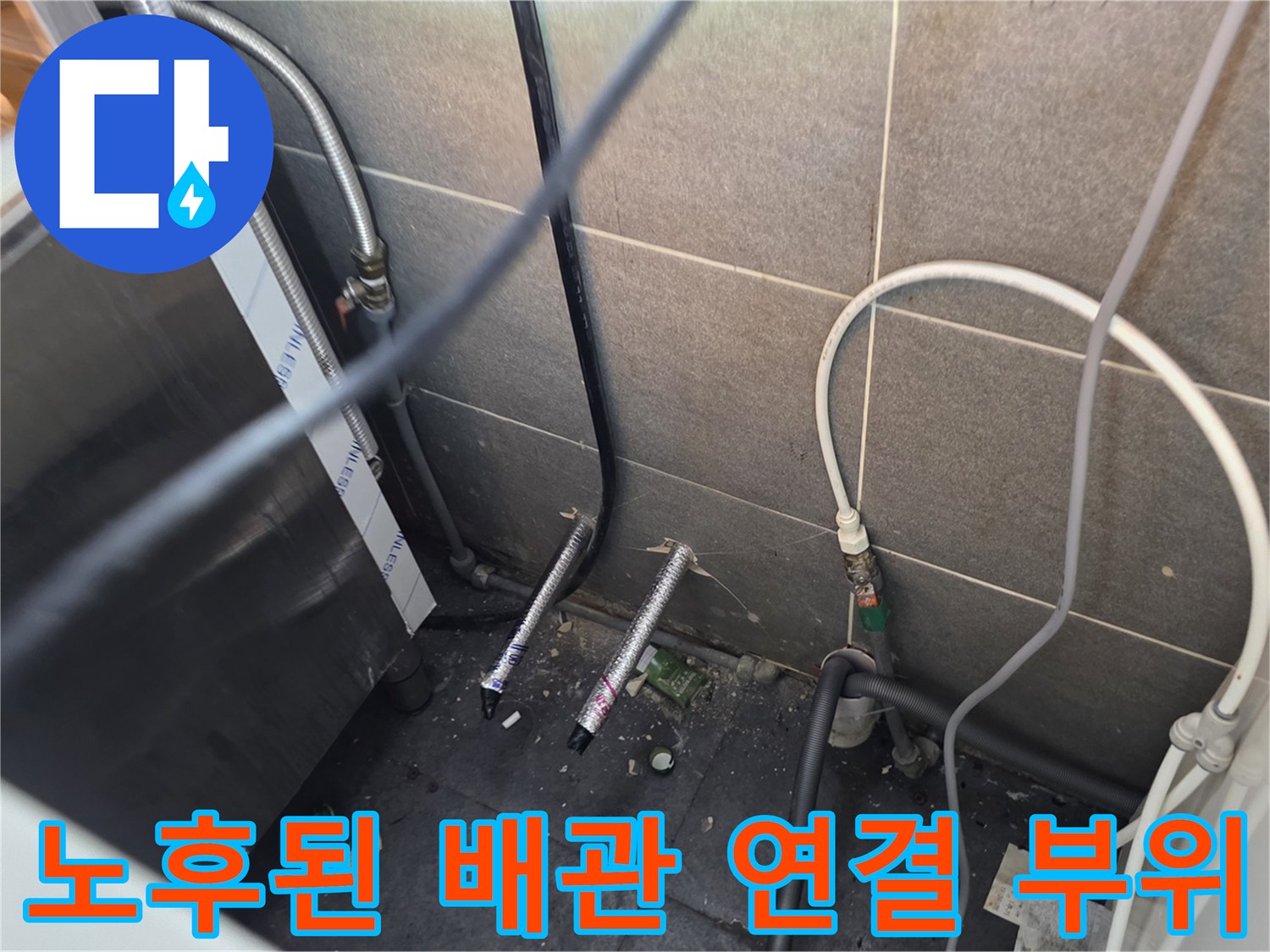 타일 벽면 아래 엉킨 수도 호스와 압력 테스트용 파란색 호스 일부