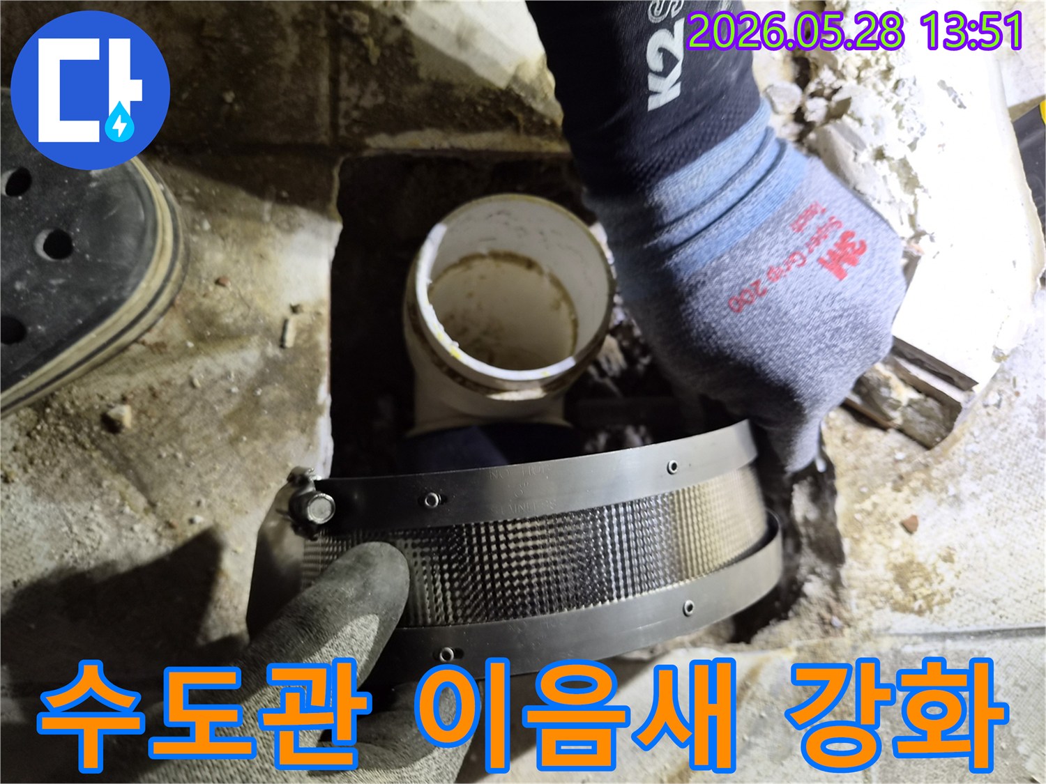 전문가가 작업용 장갑을 끼고-수도관의 이음새 누수 지점에-보강 밴드를 적용하는 모습입니다