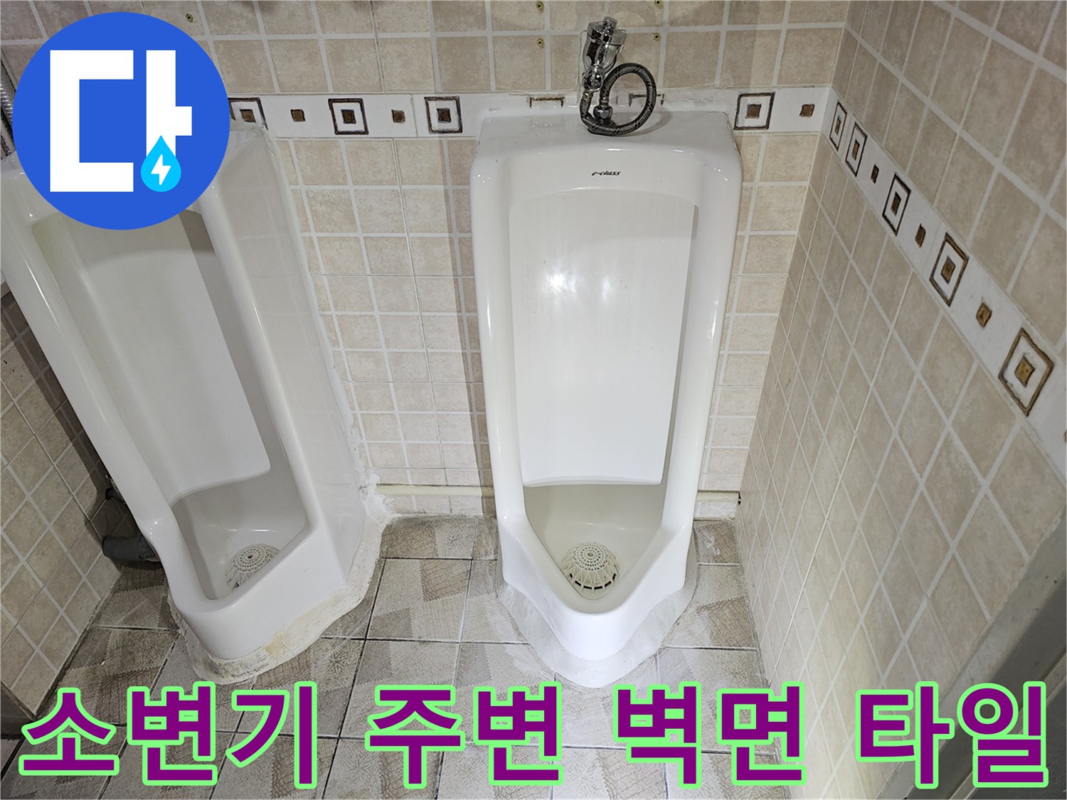 타일 벽면에 설치된 도기 소변기와 급수 밸브 모습입니다.