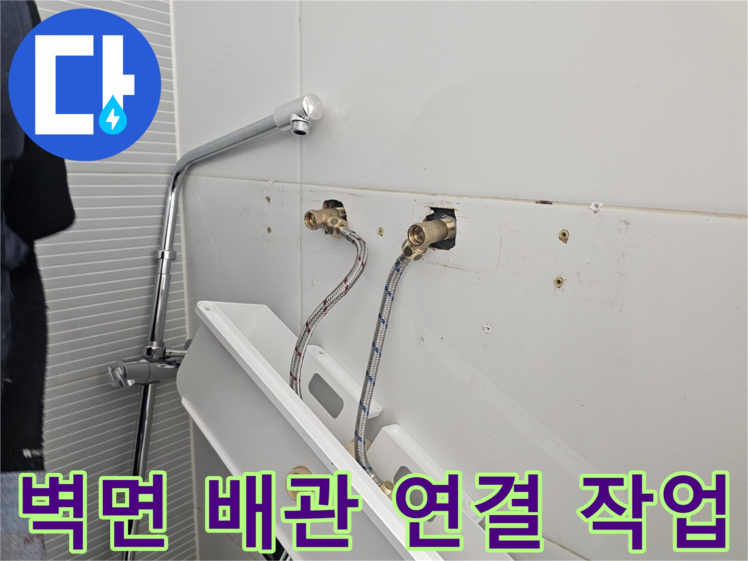 욕실 벽면 수도 부속과 고압 호스가 연결되어 있는 사진