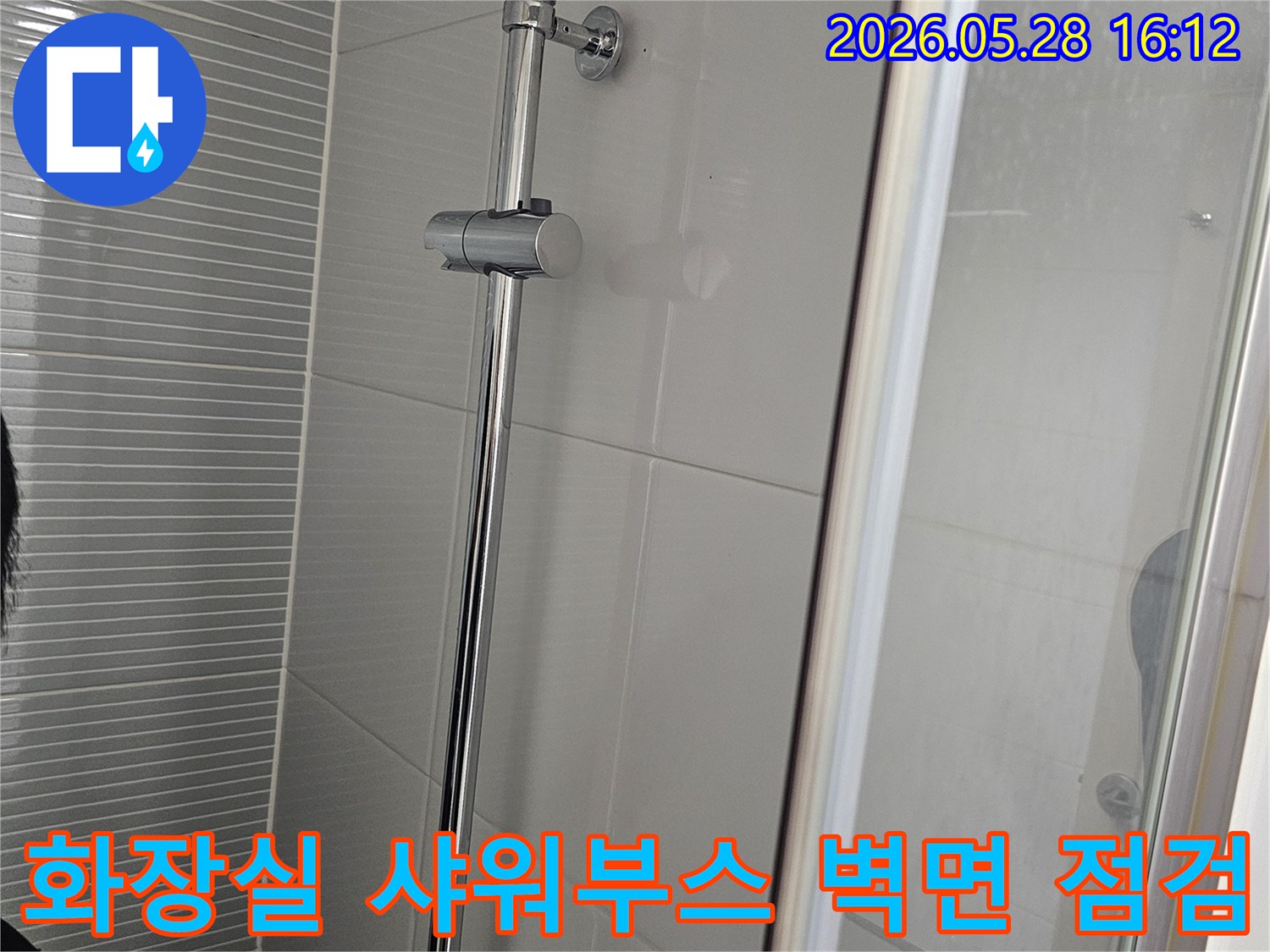 이 이미지는-누수 진단을 위해-화장실 샤워부스 벽면의-타일과 샤워바 설치 상태를-자세히 보여주고 있습니다.