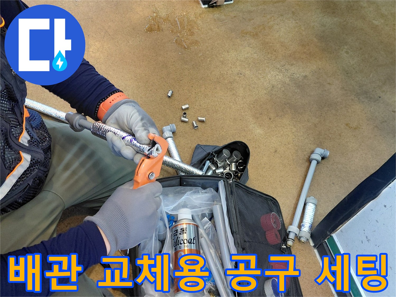 바닥에 놓인 배관 절단 도구와 수선용 부속품들을 이용한 배관 보수 작업
