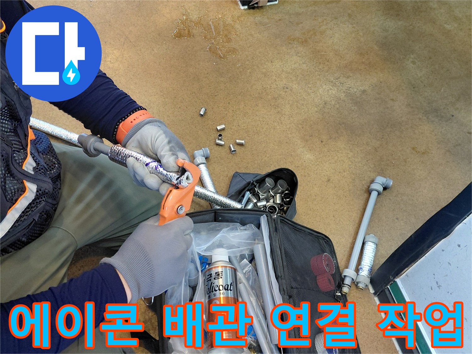 손으로 에이콘 배관의 결합 상태를 확인하며 수리를 진행하고 있습니다.