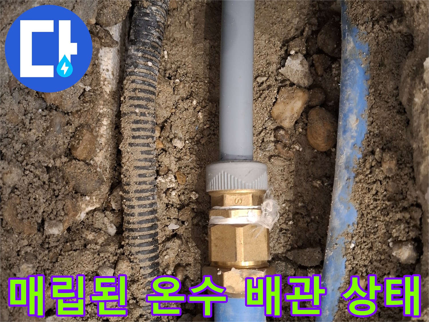 굴착된 흙 속에 드러난-손상된 금속 부속과 파란색 배관의 연결 구간