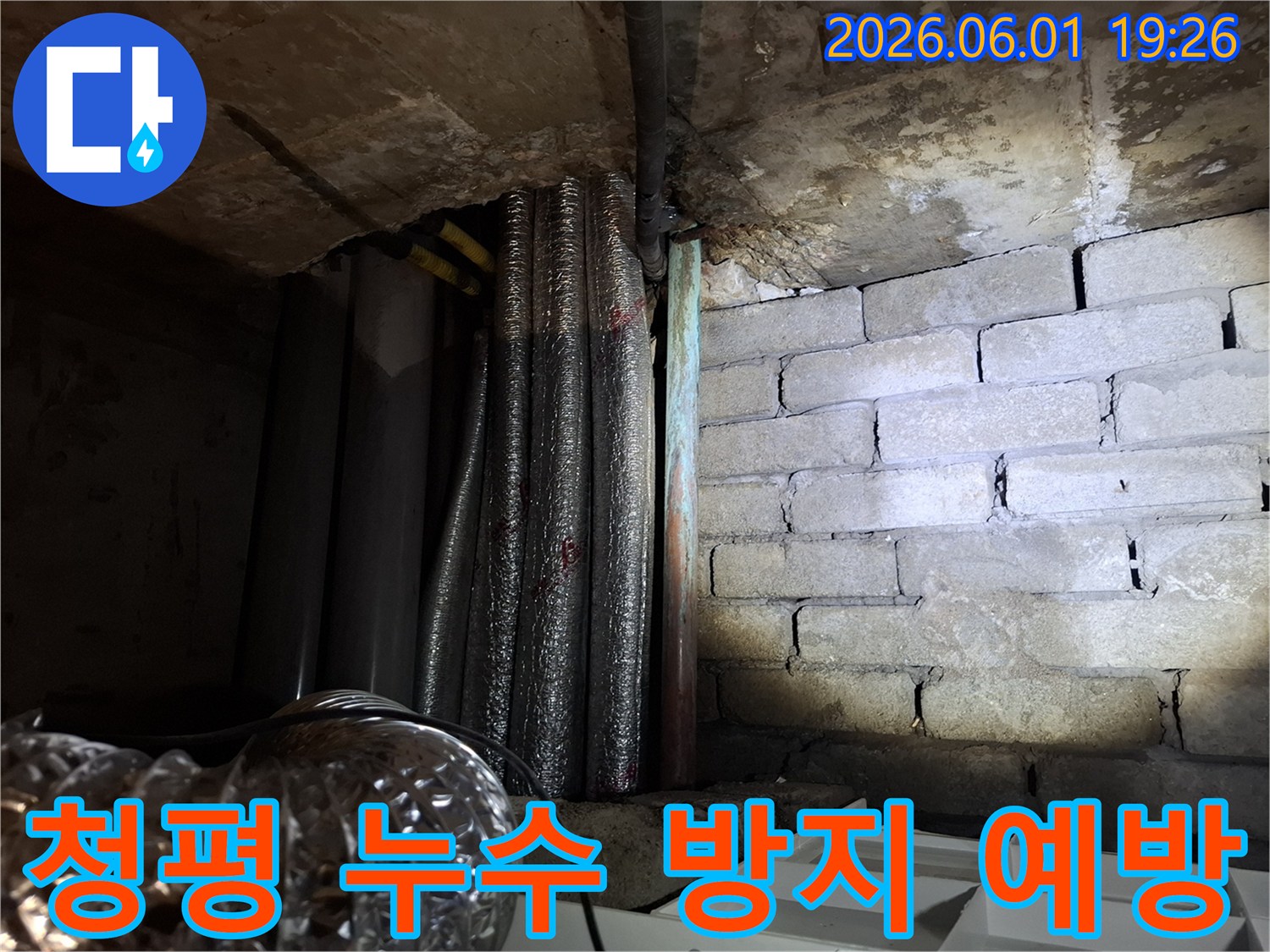 어두운 지하 공간에서-천장 배관과-벽돌 벽면의-누수 흔적을-확인하는 모습의-누수탐지 현장 사진입니다