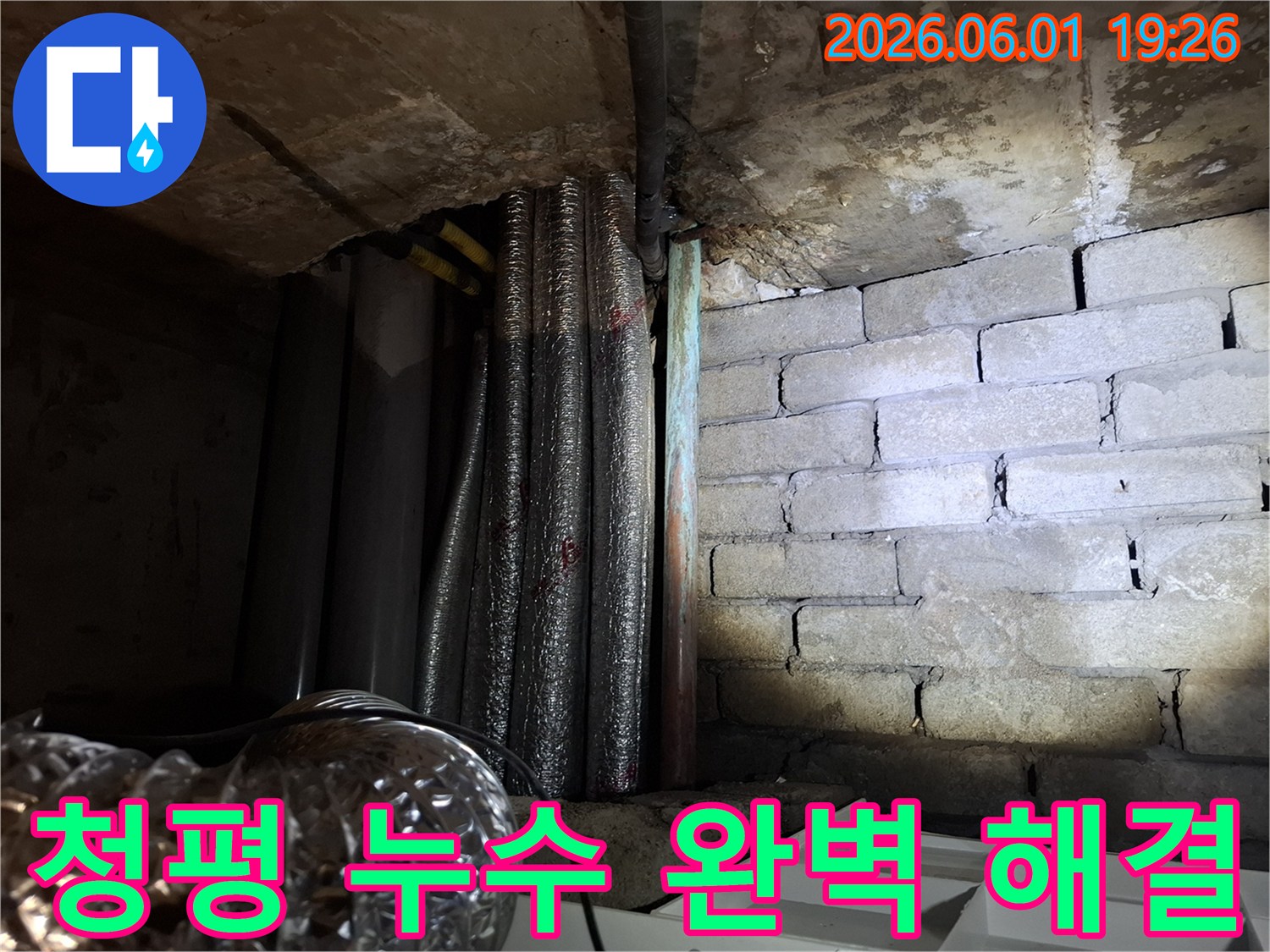 어두운 지하 공간에서-천장 배관과-벽돌 벽면의-누수 흔적을-확인하는 모습의-누수탐지 현장 사진입니다