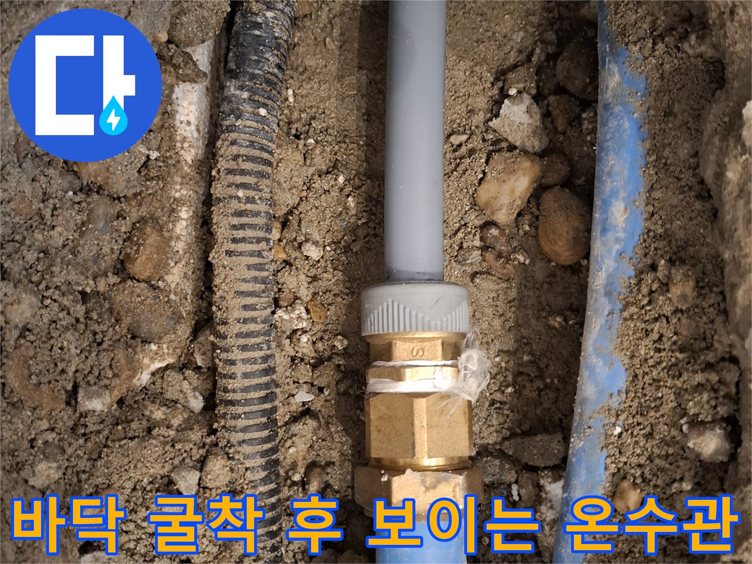 흙과 돌 사이로 드러난 파란색 온수 배관 및 금속 부품