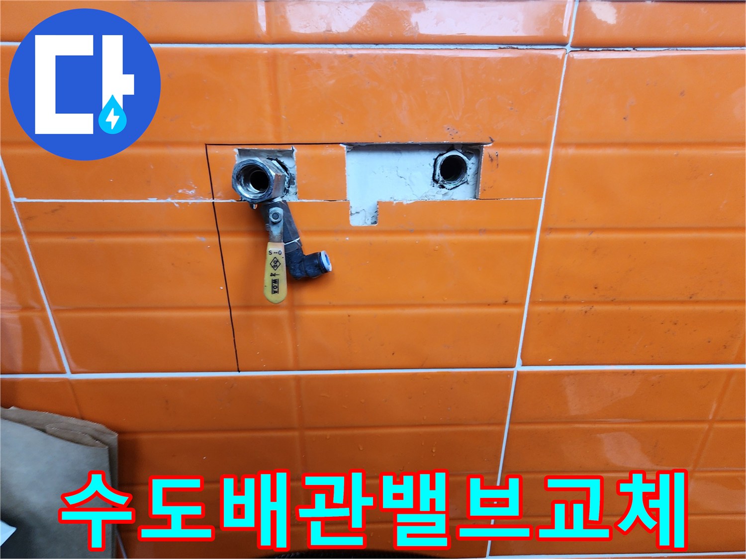 오렌지색-타일이-부분적으로-제거된-곳에-새로운-수도-밸브가-설치된-배관-수리-과정을-담은-사진입니다.