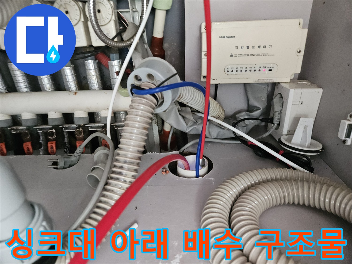 복잡하게 연결된 싱크대 하부 급수 밸브와 배수 호스