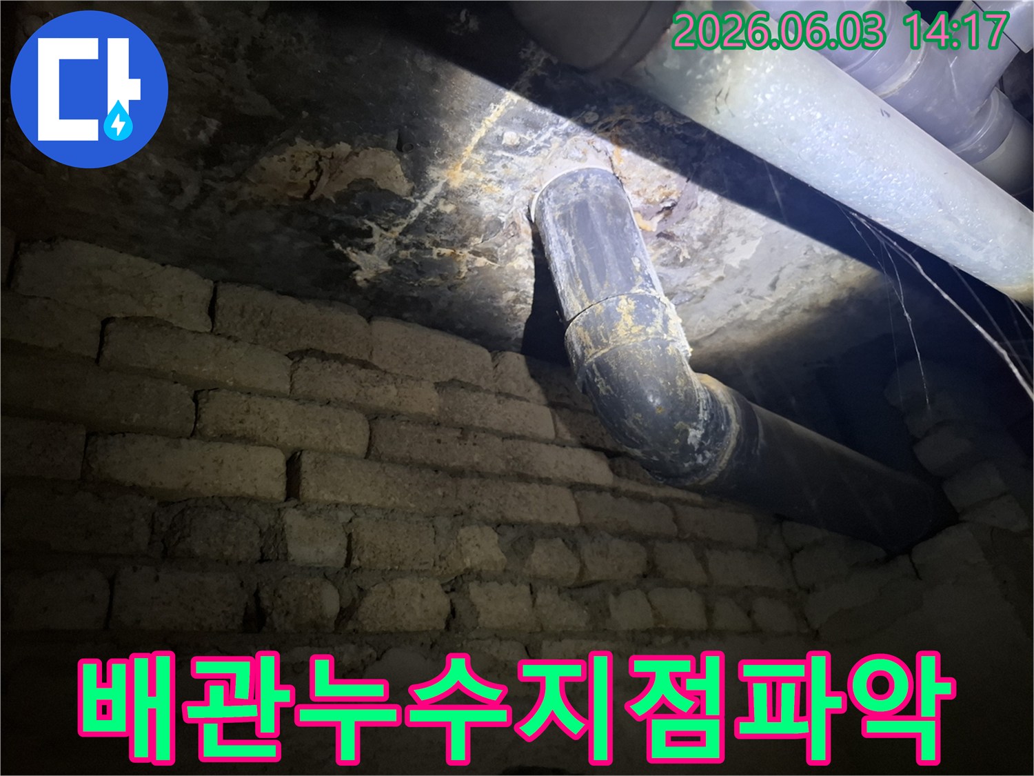 어두운 지하 공간에서-낡은 배관과-벽돌 벽에 발생한-누수 흔적을-조명으로 비춰-정밀하게 검사하는 모습