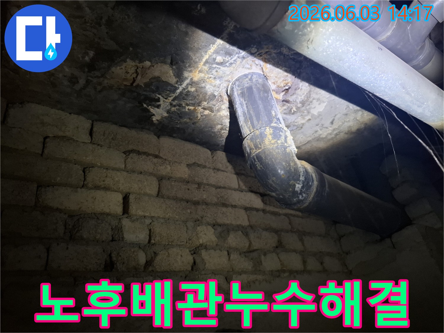 어두운 지하 공간의-낡은 벽돌 벽과-오래된 배관 주변에서-발견된 누수 흔적을-조명으로 비추어-정밀하게 진단하는 모습