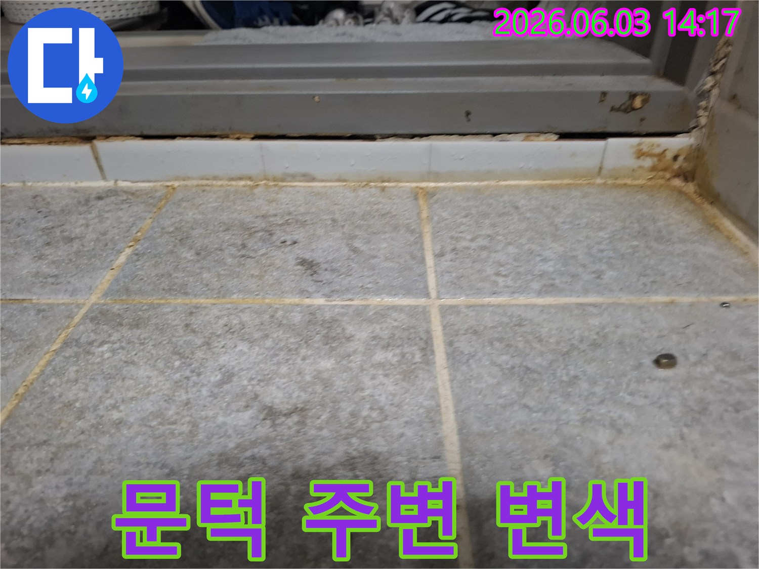 욕실 문턱 주변 타일과 줄눈에 누수로 인해 발생한-심한 변색과 오염 상태를 상세하게 보여주는 사진입니다.