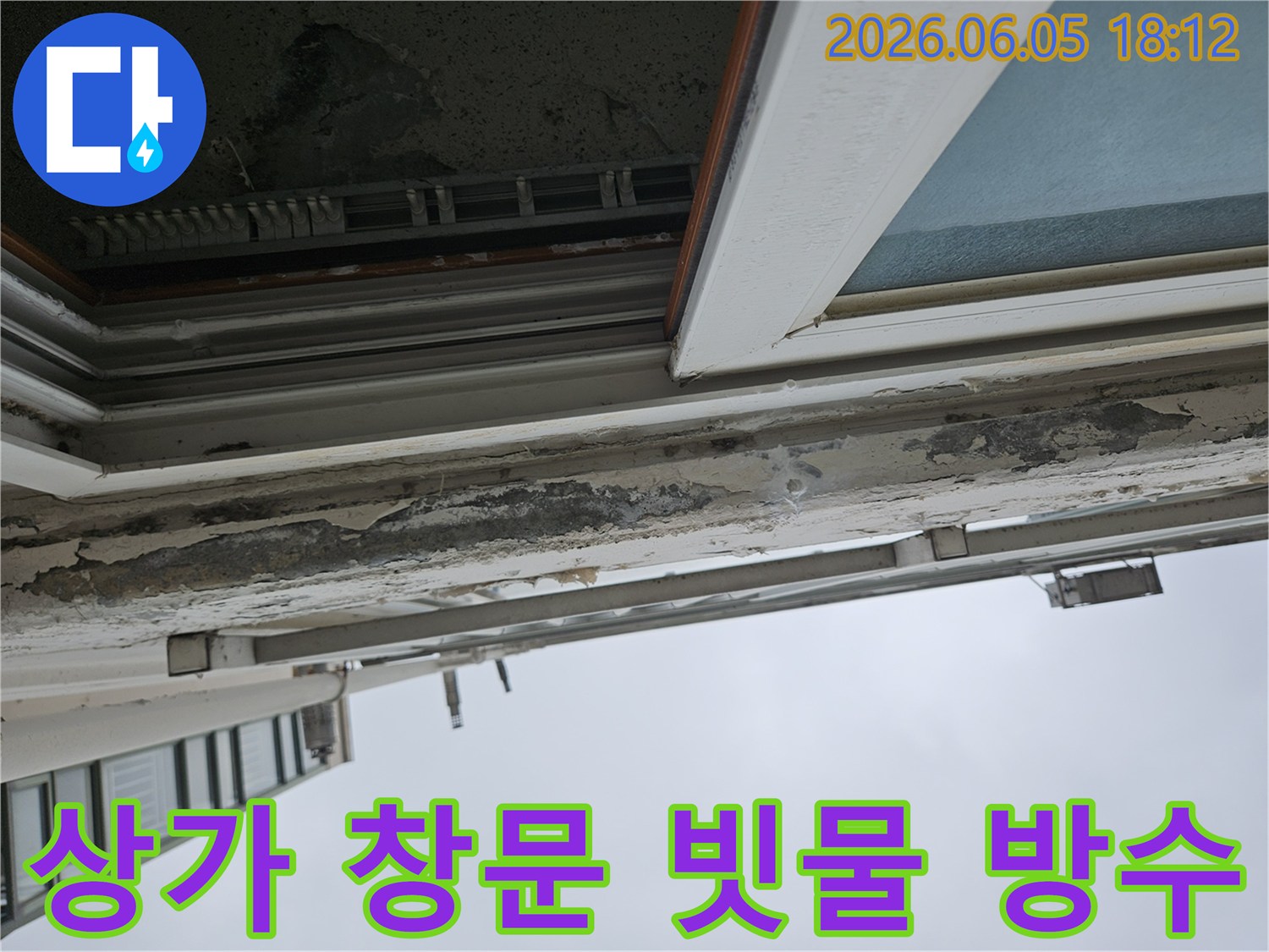 상가 건물 창문 상단부의 심각한 페인트 손상-빗물 유입으로 인한 내부 마감재 손상 우려-내부 마감재 보호를 위한 방수 작업이 필수적