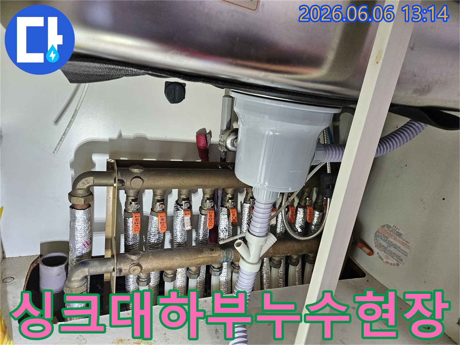 싱크대 아래에 위치한-보일러 분배기에서-물이 새는 현장을-전문가가 점검하는 모습