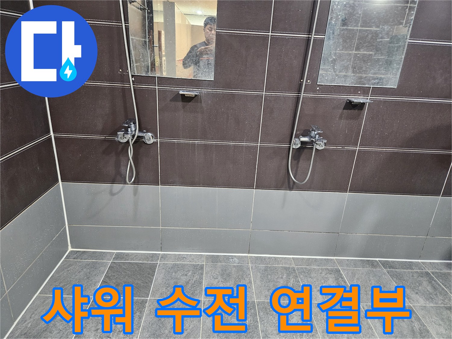 어두운 톤의 욕실 타일과 금속 재질의 샤워 수전