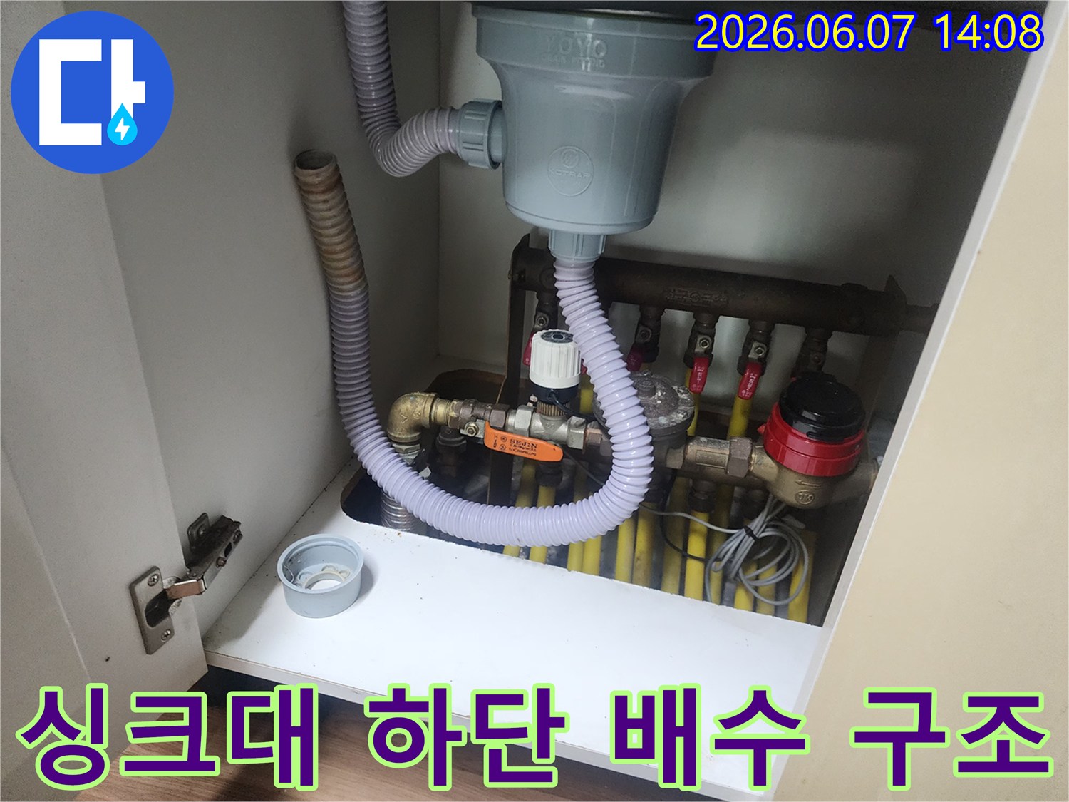 싱크대 하부장 내부에 노출된 배수 호스와 밸브 장치