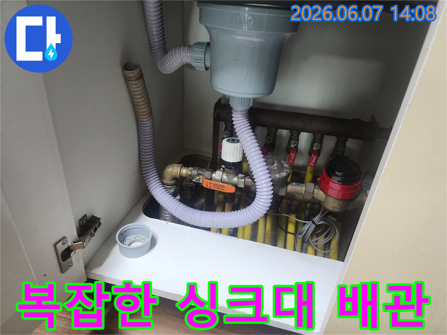 주방 싱크대 하부장-연결된 여러 개의 노란색 배관과 회색 주름관의 모습입니다.