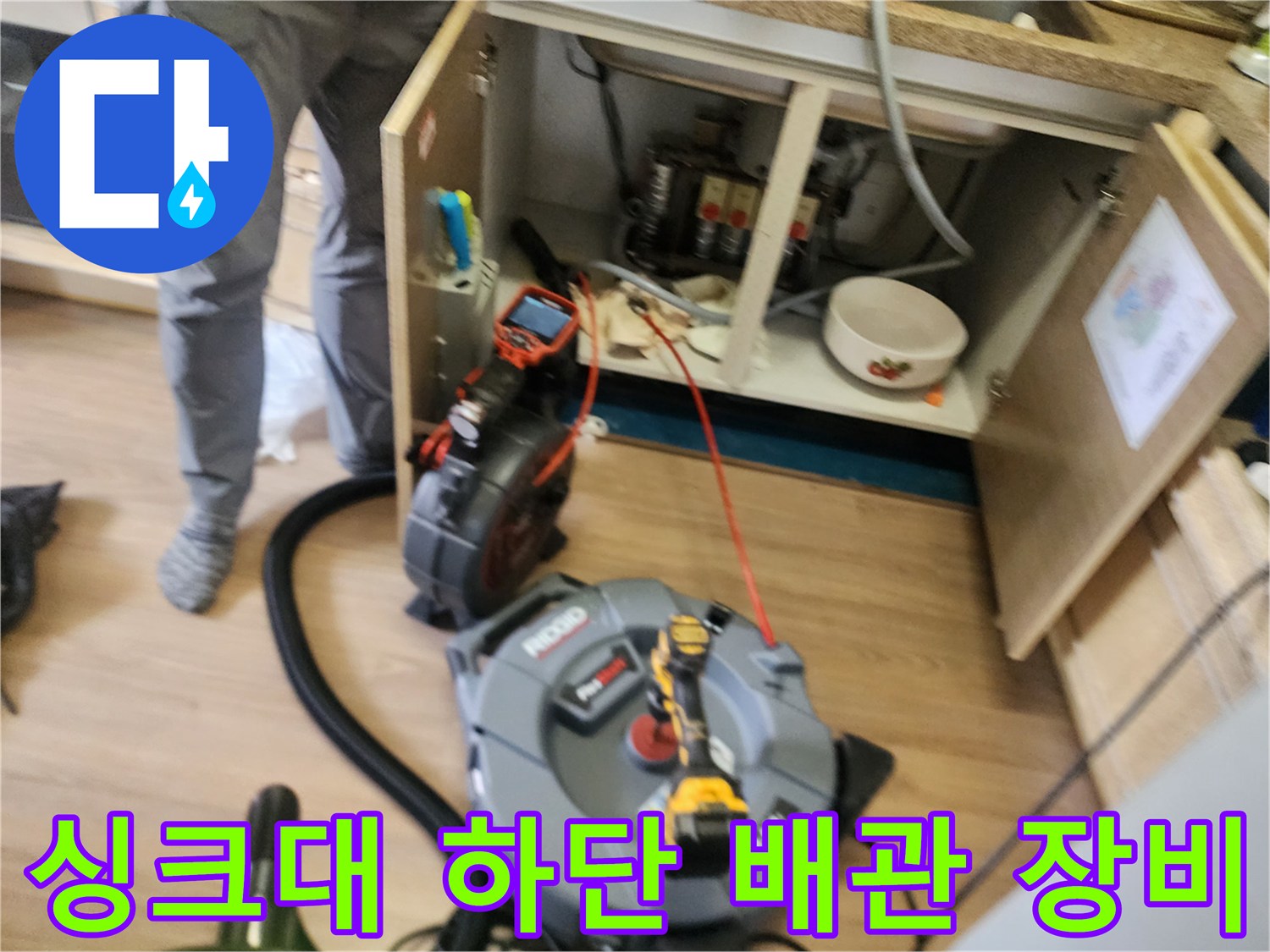 싱크대 하부장 아래에 배치된 배관 스케일링 장비와 석션기