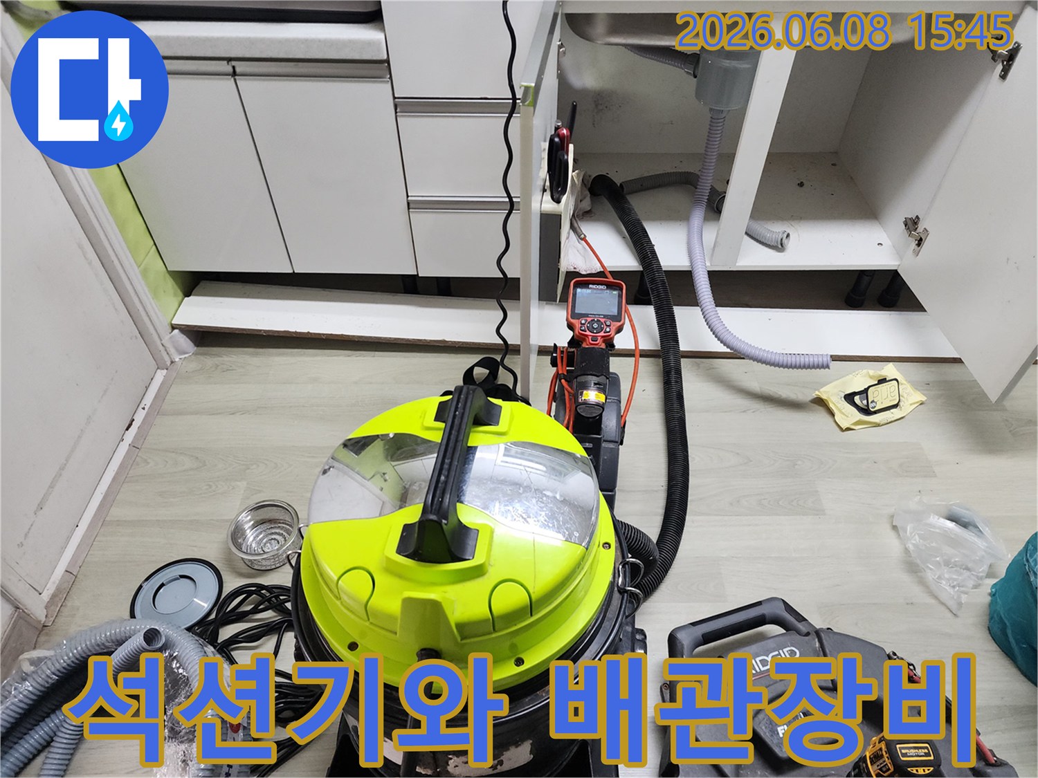 싱크대 하부장 내부-배관 청소용 석션기와 플렉스 샤프트 장비가 놓여 있는 모습