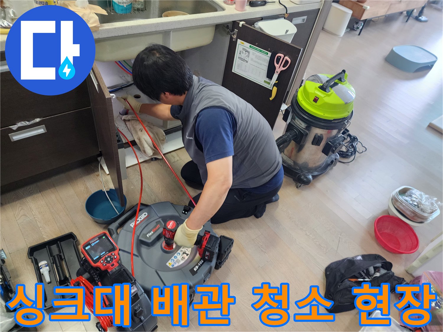 싱크대 밑 공간에서 스케일링 노즐을 조절하며 배관 내부를 세척하는 과정