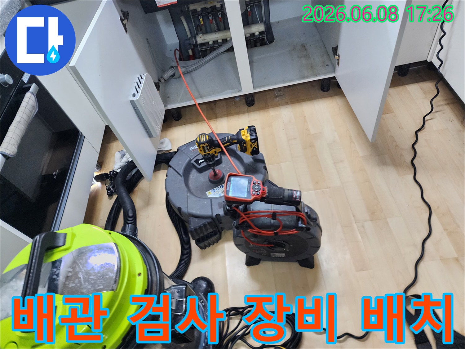 싱크대 하단 배관 부근에-내시경과 전동 드릴 등-작업 도구를 배치한 장면입니다.