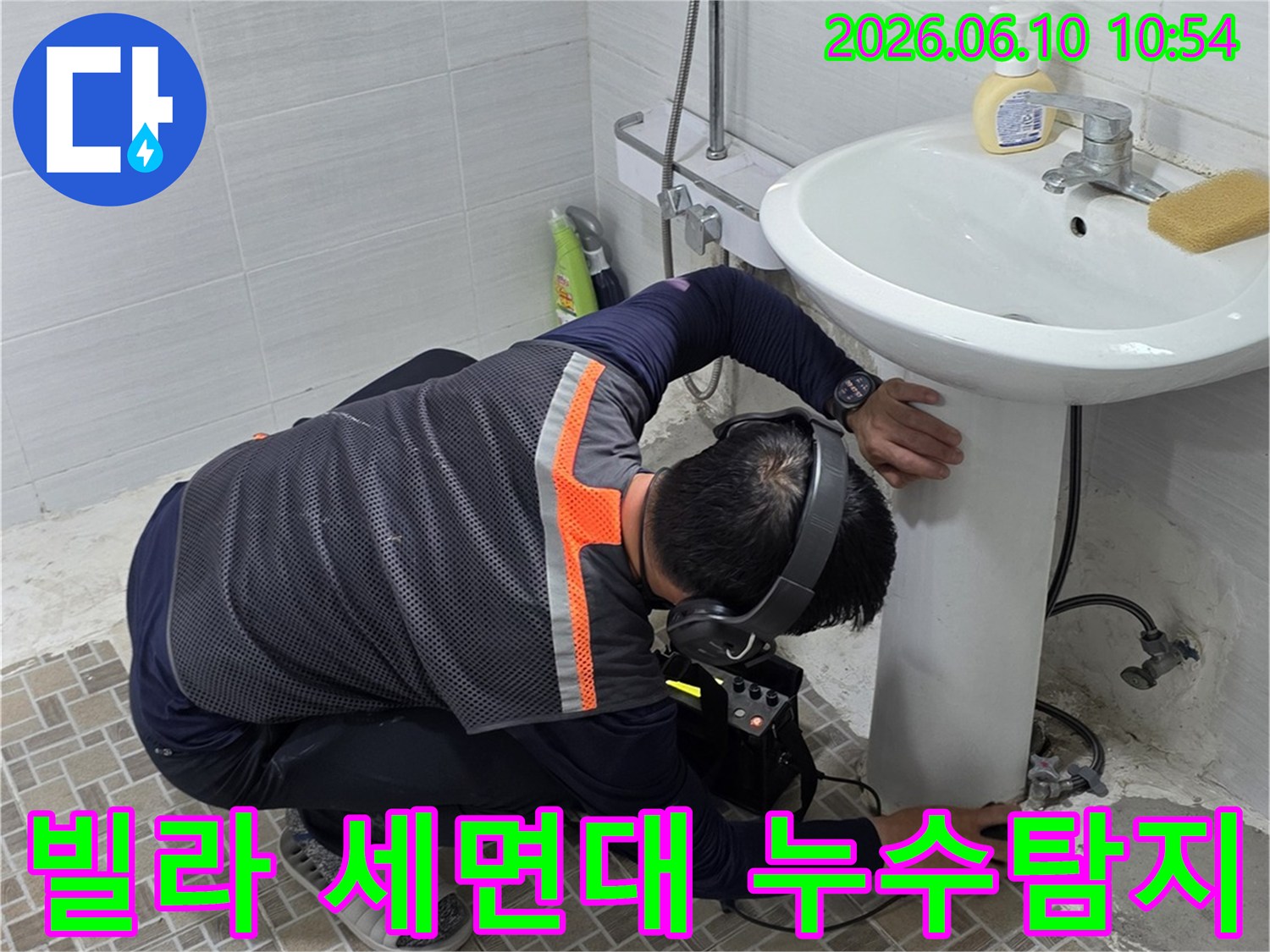 빌라 욕실에서-세면대 아래 배관의-누수 지점을 찾기 위해-청음식 탐지기를 사용하는-전문 누수 엔지니어의 모습