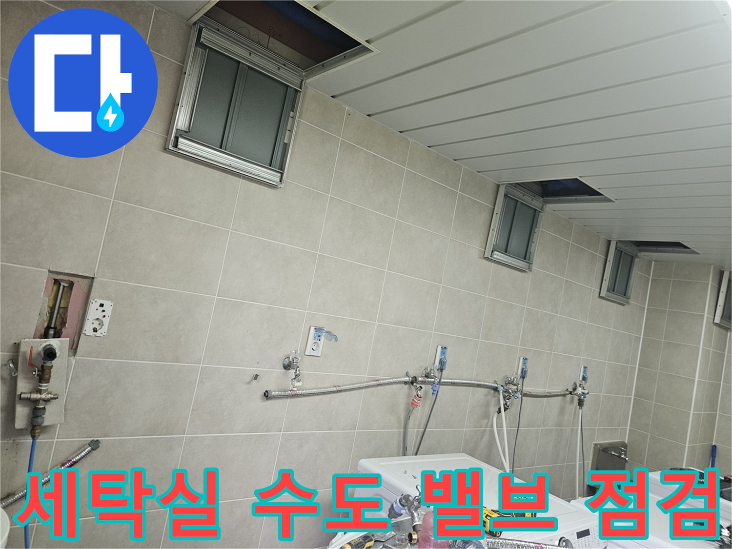 세탁실 벽면에 노출된 은색 배관 및 수도 연결 부속품