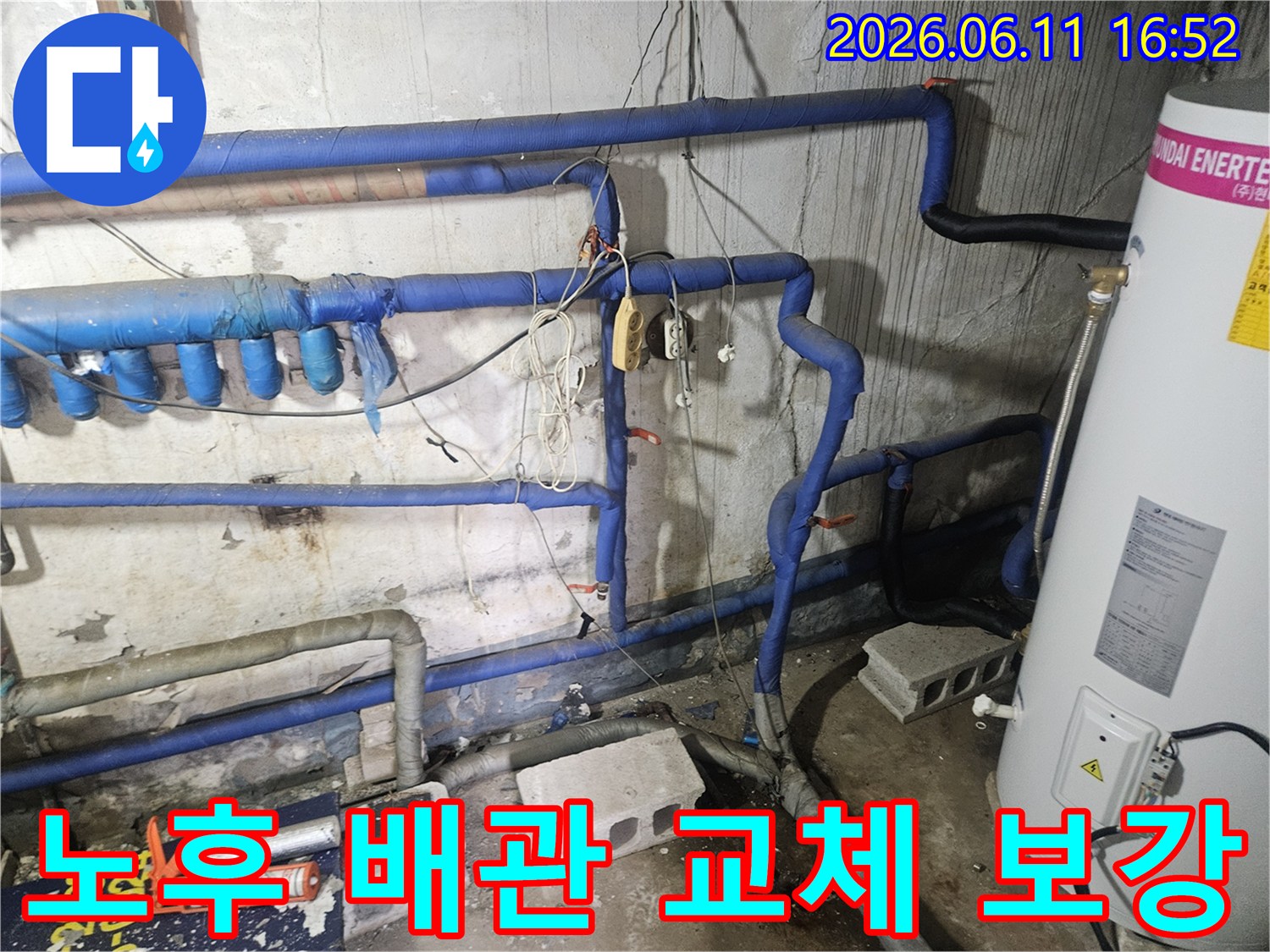 오래된 콘크리트 벽면과-파란색 보온재로 감싸인-다양한 배관들이 보이는-누수 현장의 모습입니다