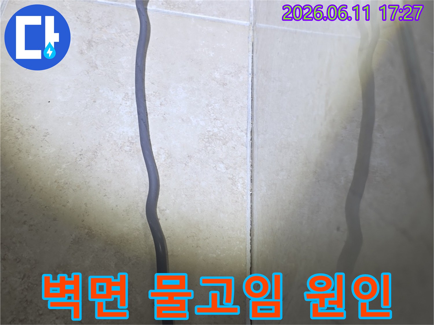 욕실 벽면 타일 하단부에-물이 스며들어 습기가 올라온 현장을 보여주는 사진입니다