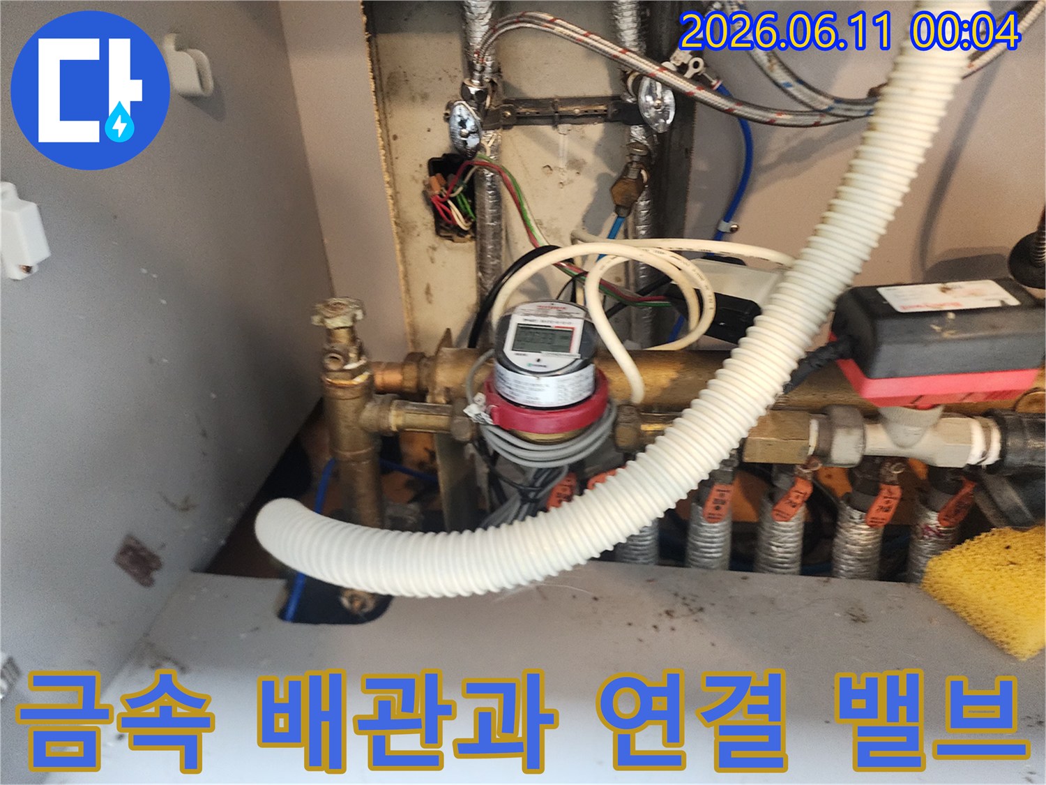 은색 금속 관과 조절용 밸브가 설치된 싱크대 하부 배관의 상세 모습입니다.