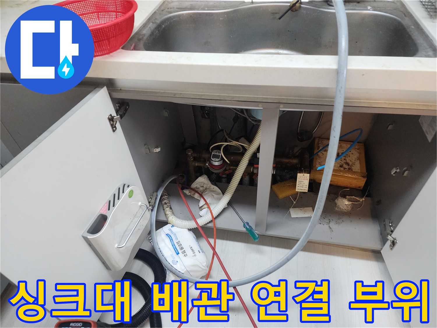 주방 싱크대 아래쪽-복잡하게 얽힌 배수 호스와 배관 연결부