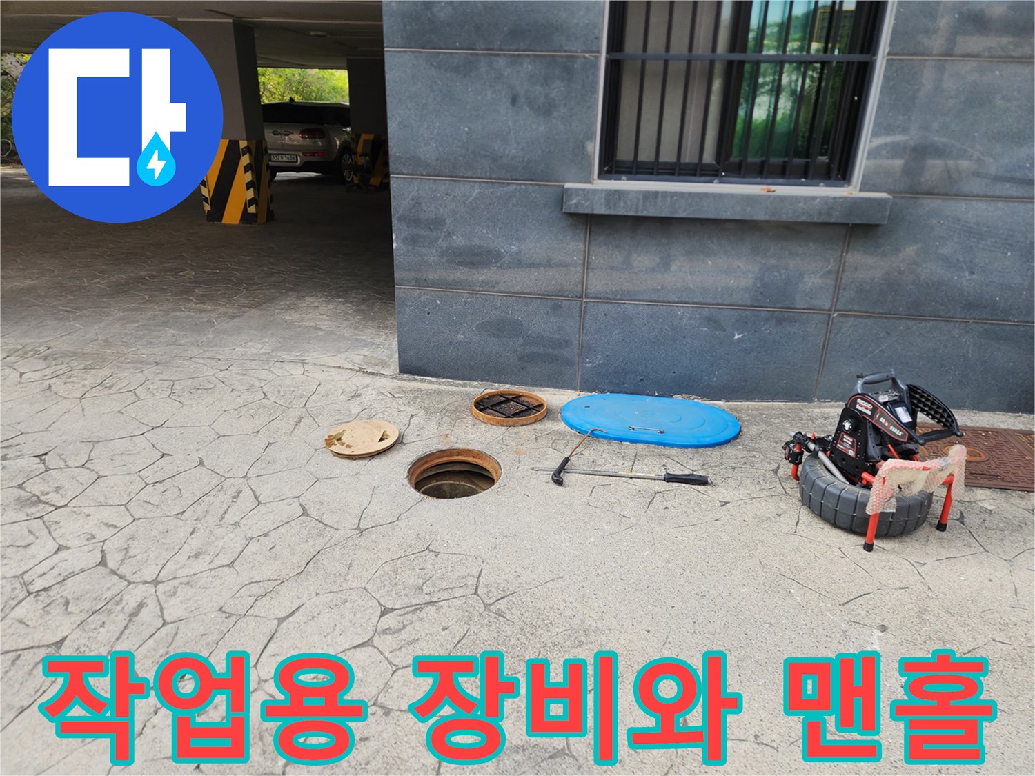 맨홀 주변에 배치된 고압 세척기 및 내시맨홀 점검 도구