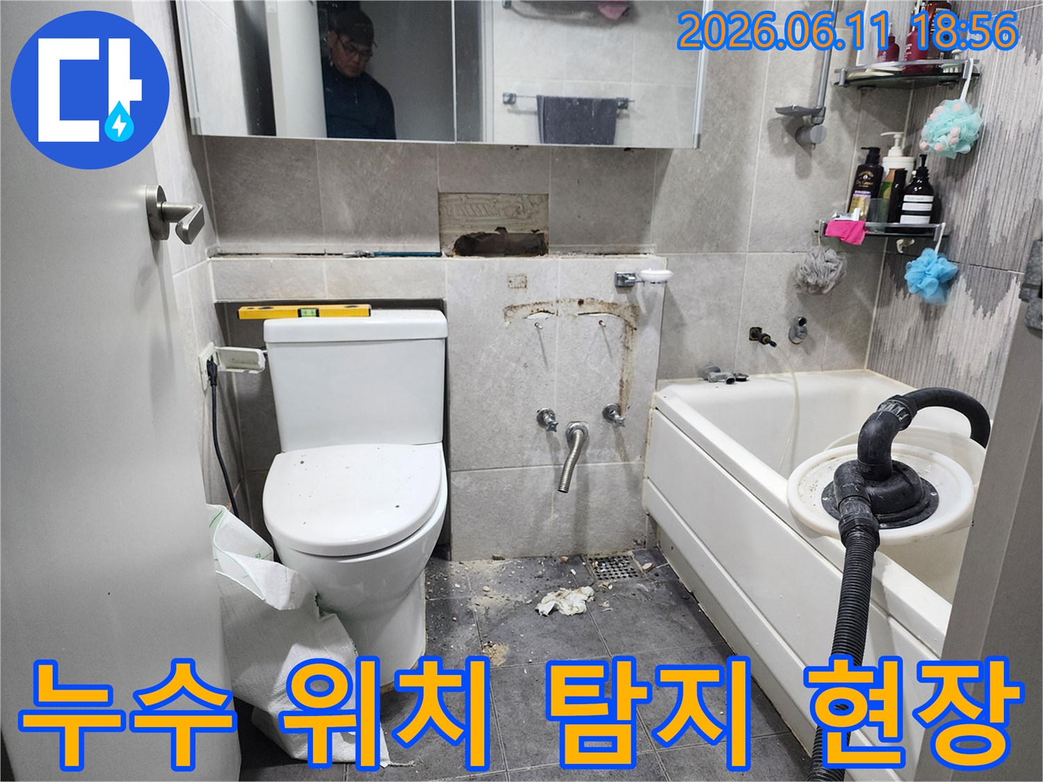 이 이미지는-서울 동대문구의 한 욕실에서-누수 발생 지점을 정확히 파악하기 위해-타일을 일부 제거하고-정밀 탐지 장비를 활용하는-작업 현장을 보여줍니다