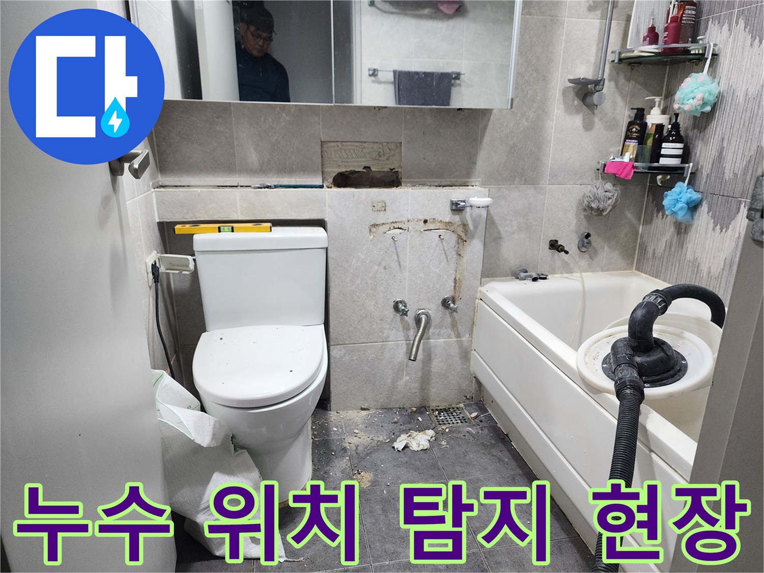 이 이미지는-서울 동대문구의 한 욕실에서-누수 발생 지점을 정확히 파악하기 위해-타일을 일부 제거하고-정밀 탐지 장비를 활용하는-작업 현장을 보여줍니다