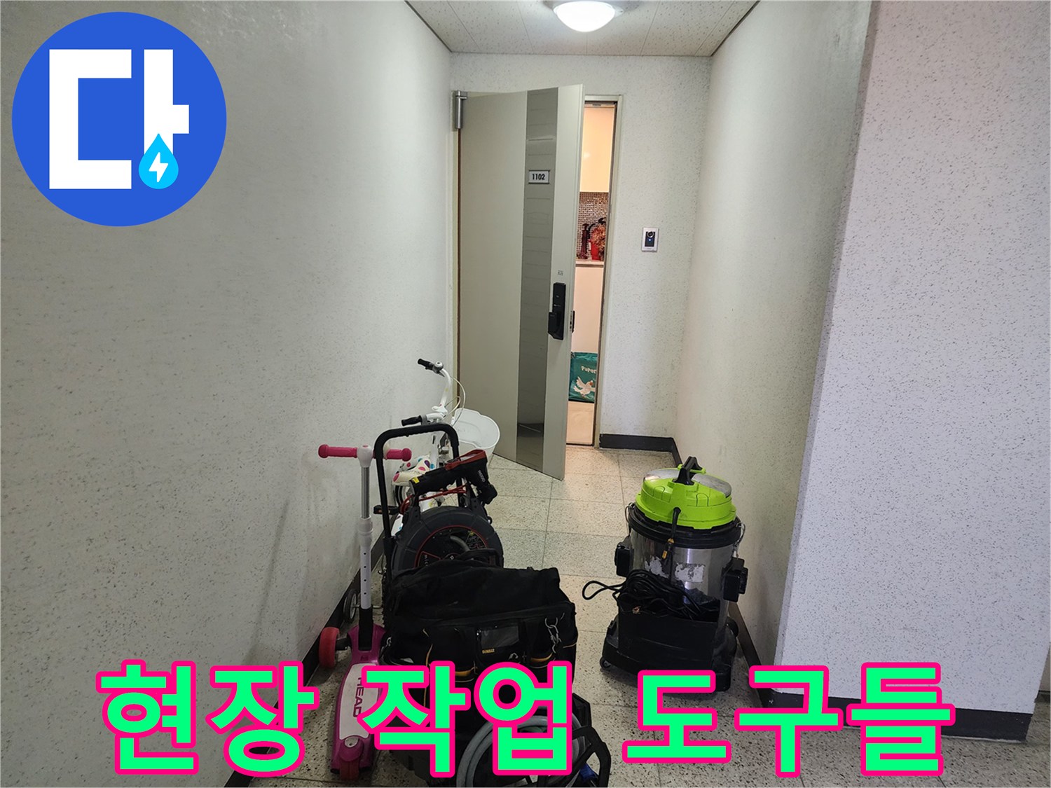 복도 바닥에 준비된 배관 청소용 진공 장비와 공구함