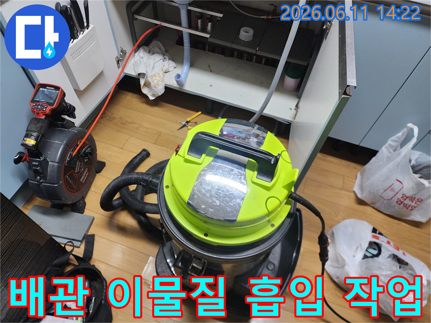 석션 호스가 연결된-대형 청소 장비가-싱크대 하부장에 놓여 있음