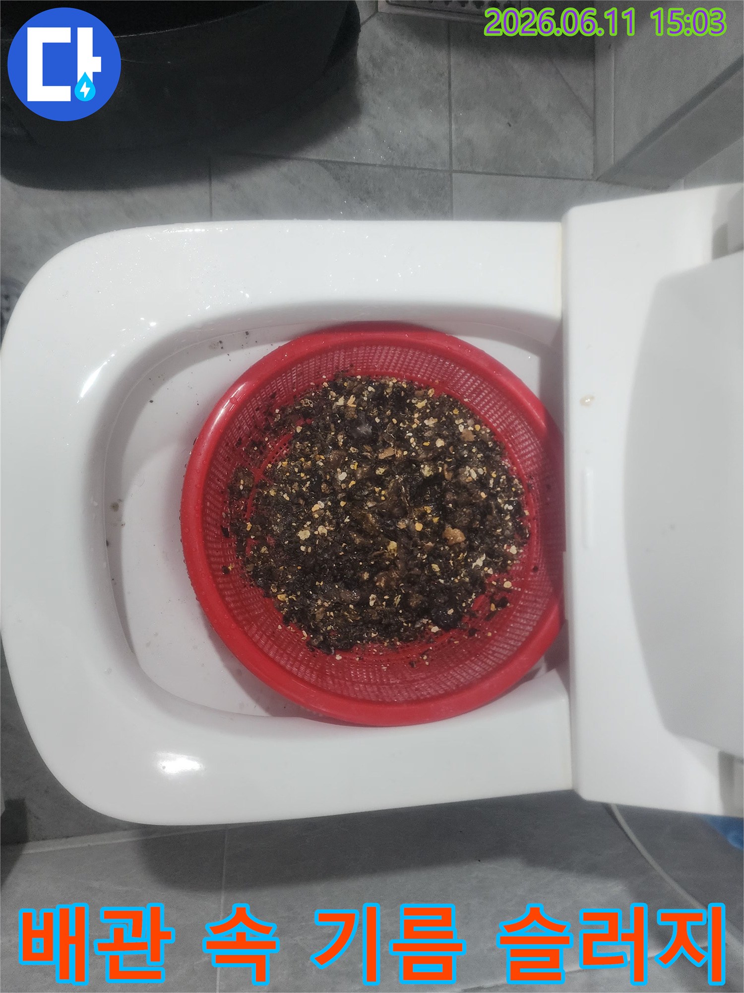 빨간색 채에 걸러진 배관 내부의 검은색 기름 슬러지 덩어리들