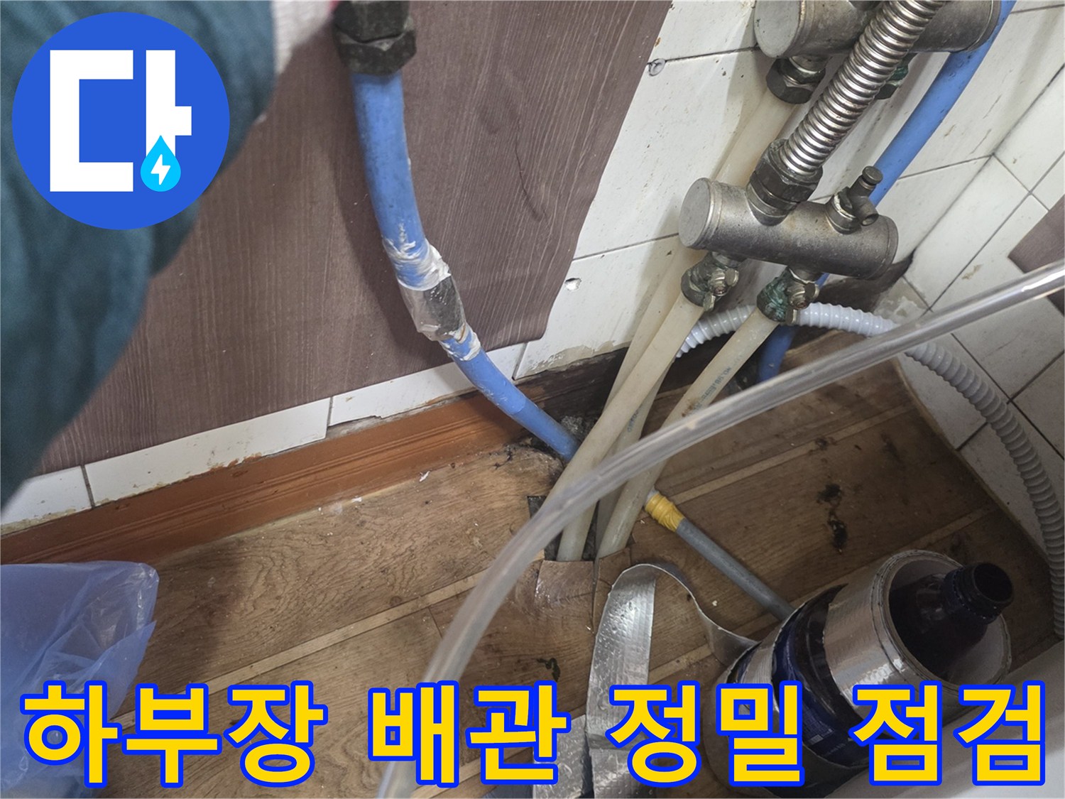 싱크대 하부장의 복잡한 수도 배관과 압력 측정 장비의 연결 상태
