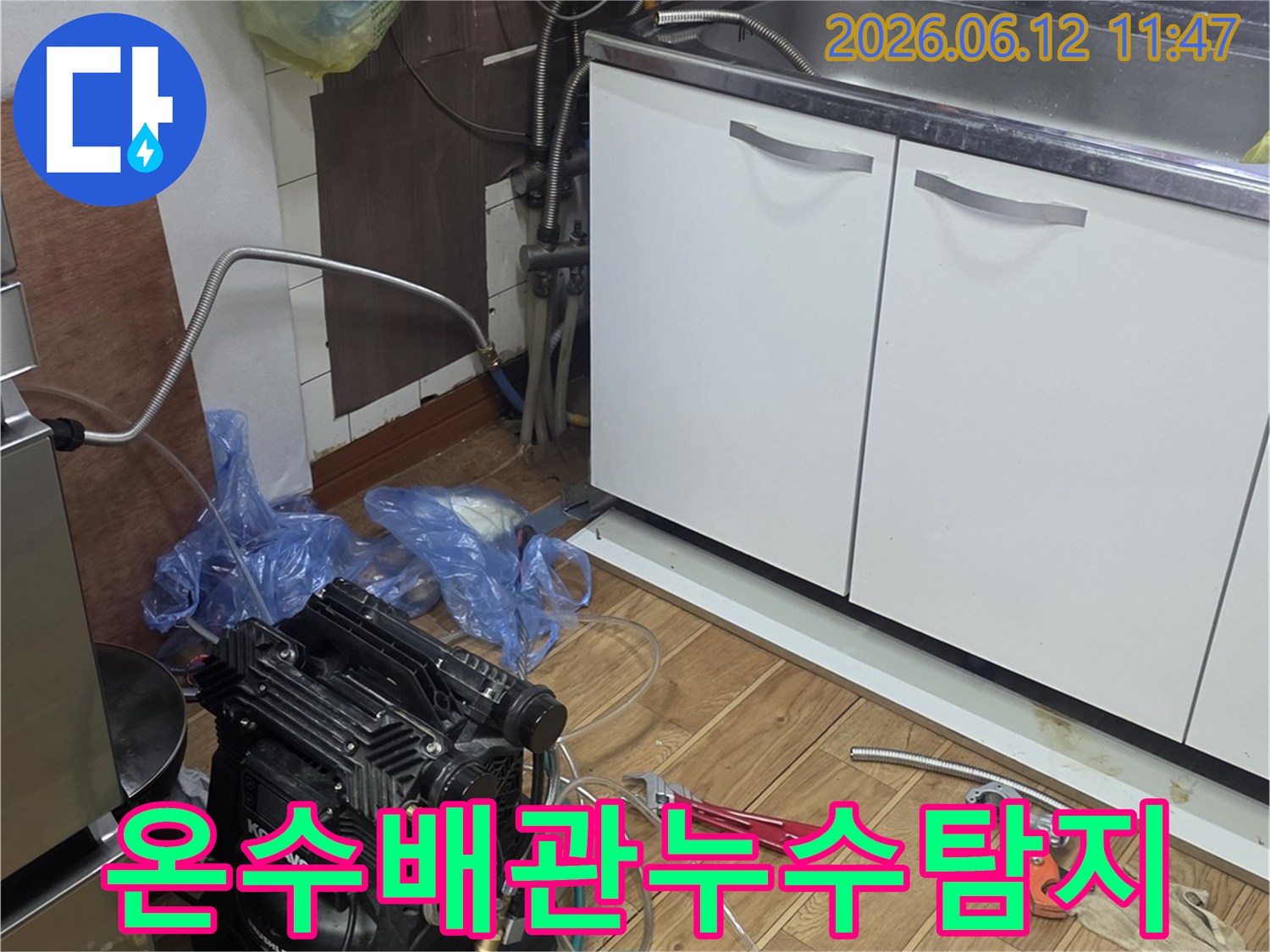 주방 싱크대 하부에서-온수 배관 누수를 탐지하기 위해-전문 장비를 연결하고-점검하는 작업 현장