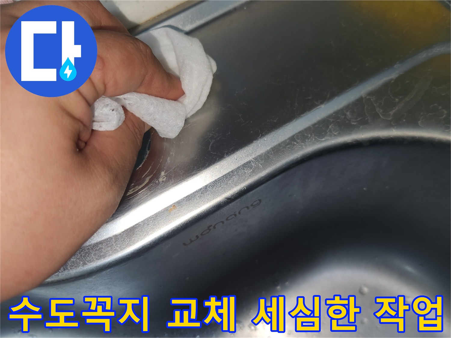 싱크대 상판의 수도꼭지 구멍 주변을- 젖은 천으로 꼼꼼히 닦아내며- 세심하게 청소하는 손의 모습입니다