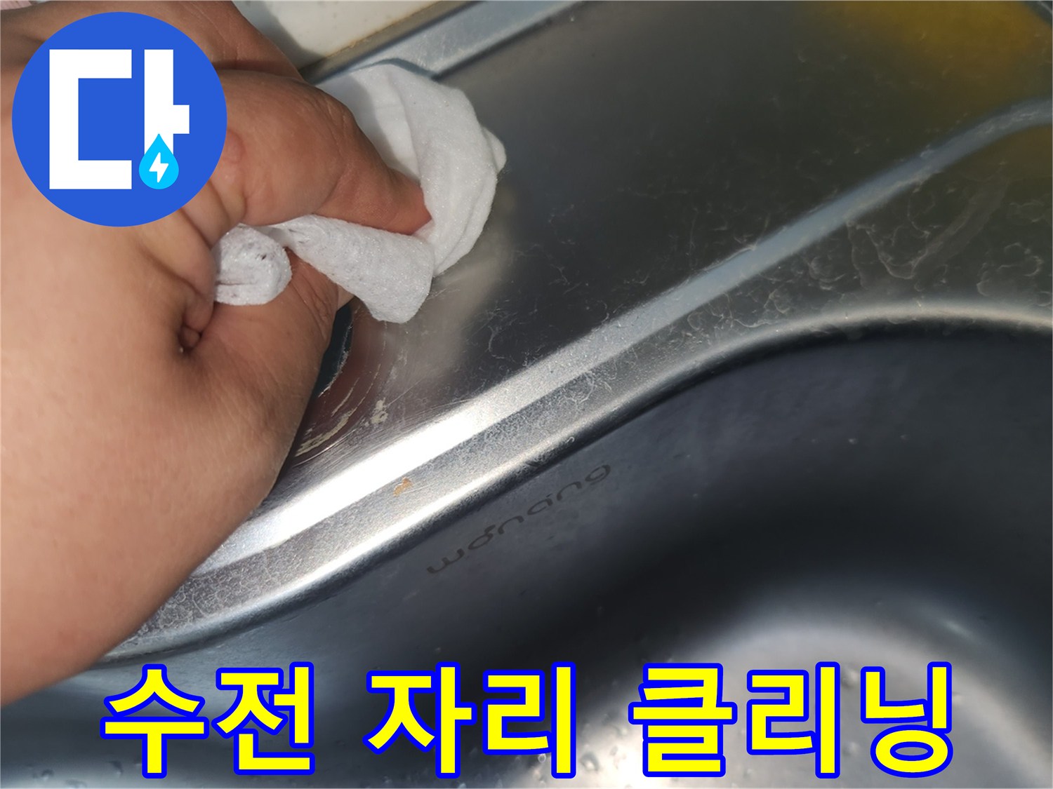 싱크대 상판의 수전 구멍 주변을- 젖은 천으로 꼼꼼히 닦아내며- 깨끗하게 만드는 손의 모습입니다