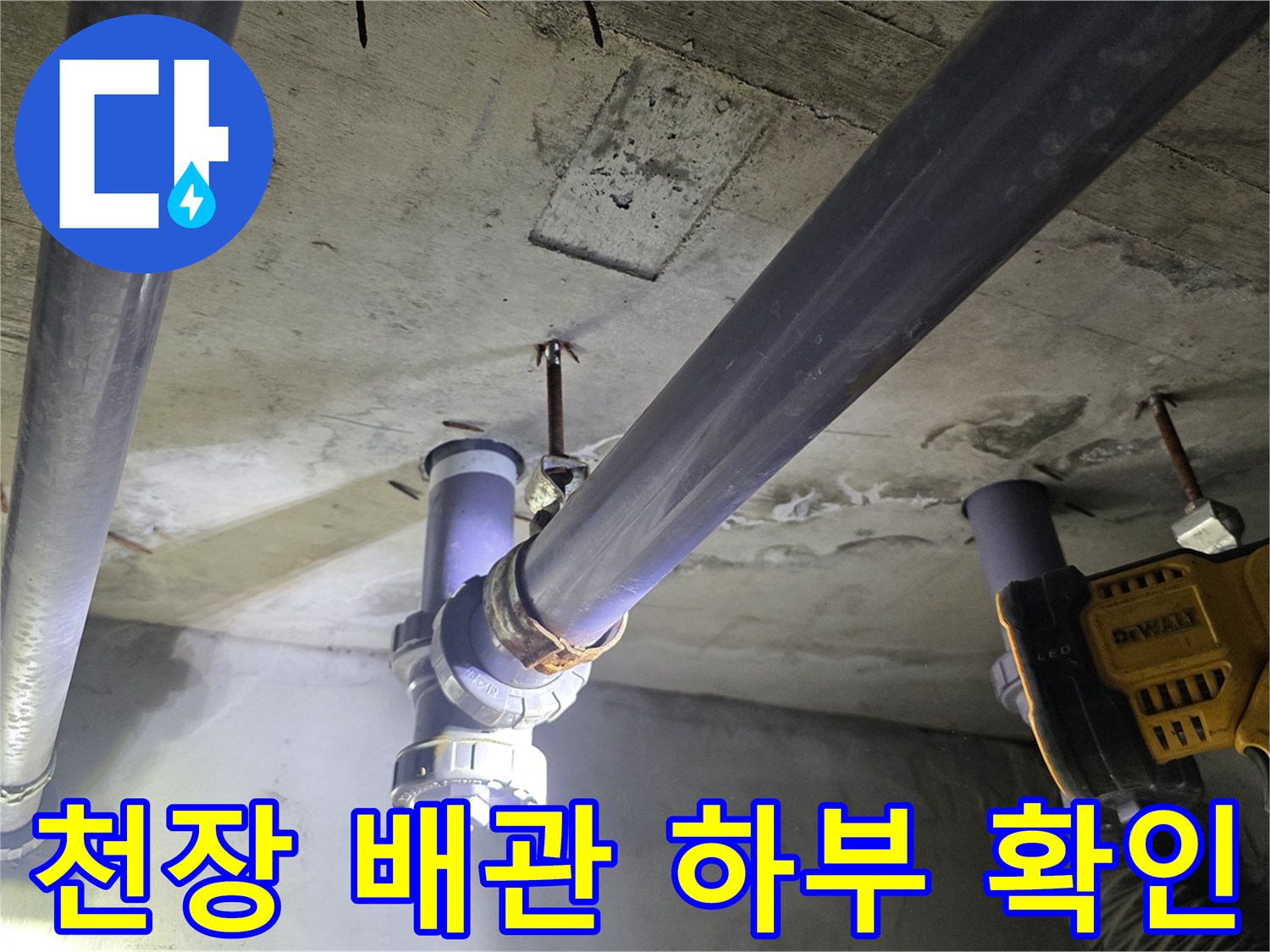 천장에 노출된 굵은 배수 파이프와 연결 부위의 근접 촬영