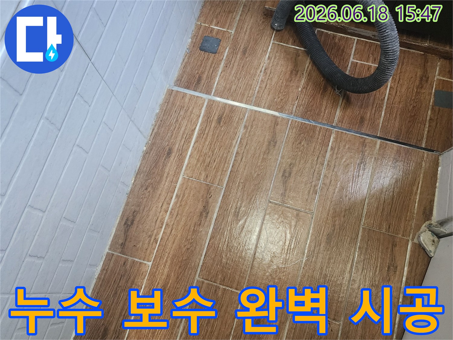 염창동 아파트에서 누수 보수를 위한 완벽한 시공을 약속하며 탐지 작업이 진행 중인 현장입니다-바닥 타일 위에 검은색 호스가 놓여 있습니다.