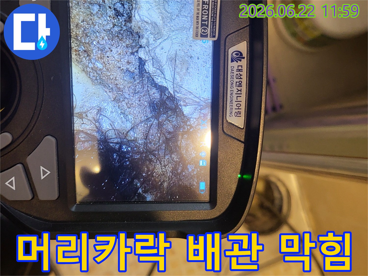 누수 탐지 전문가가-배관 내시경으로 오수관 내부를 촬영하여-머리카락과 슬러지로 막힌 상태를 확인하는 모습
