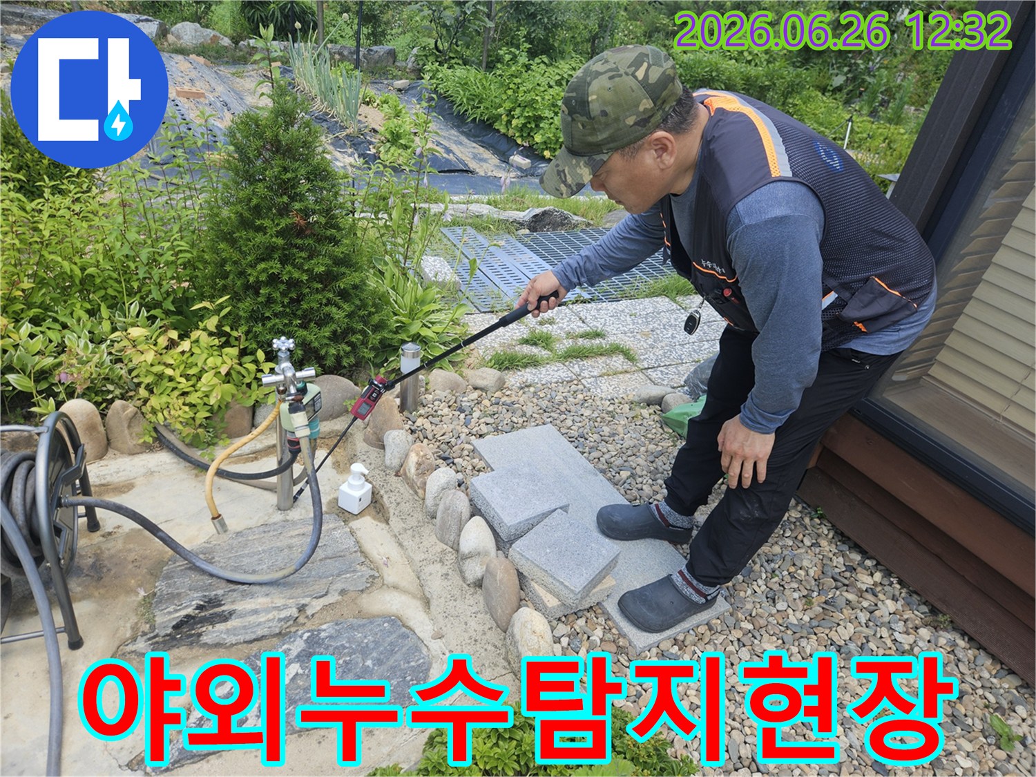 누수-전문가가-야외-수도관-주변에서-누수-탐지-장비를-이용해-정밀하게-점검하는-장면입니다.