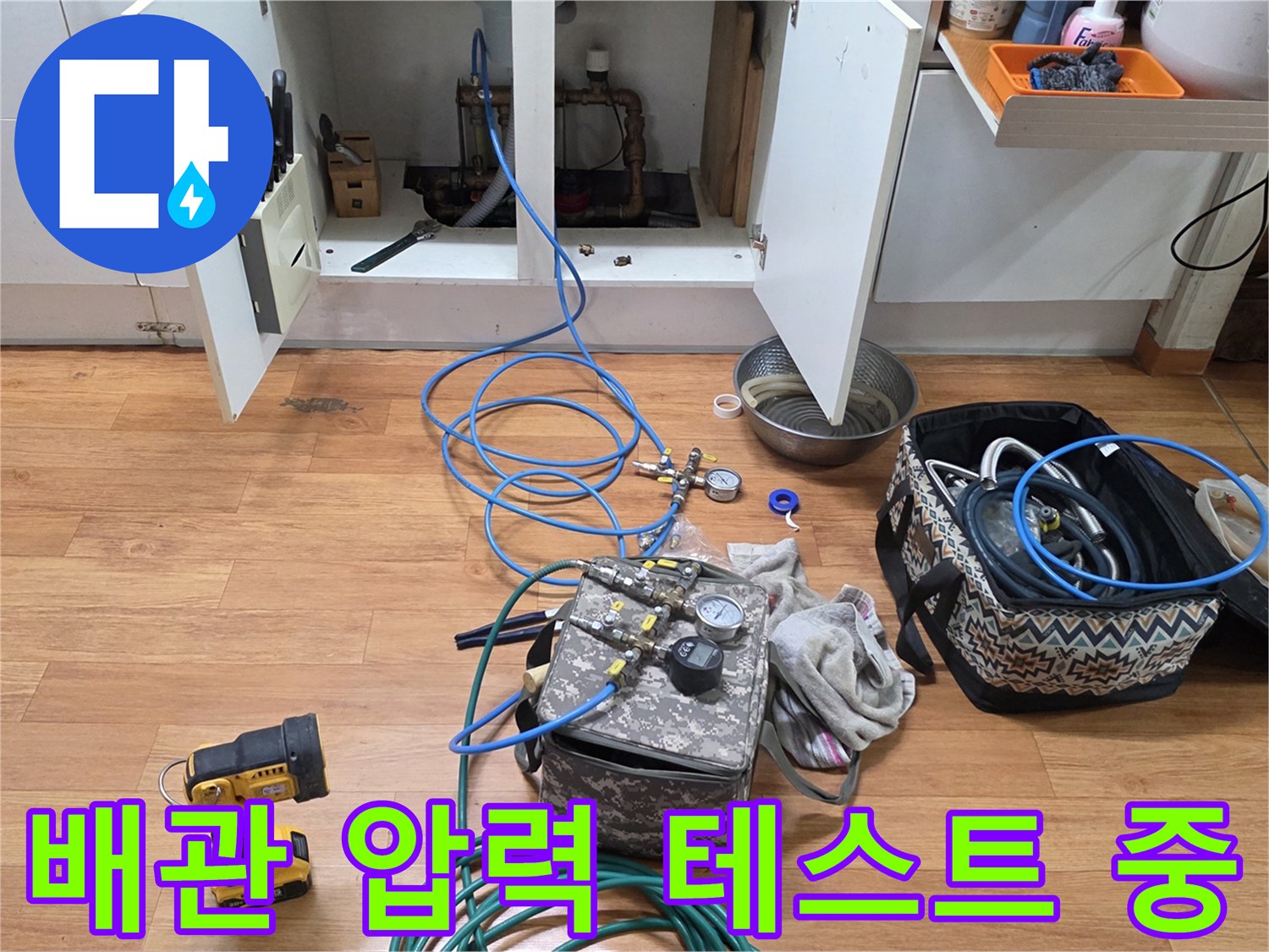 싱크대 밑 배관 연결 부위에 연결된 파란색 에어 호스와 압력 게이지 장치