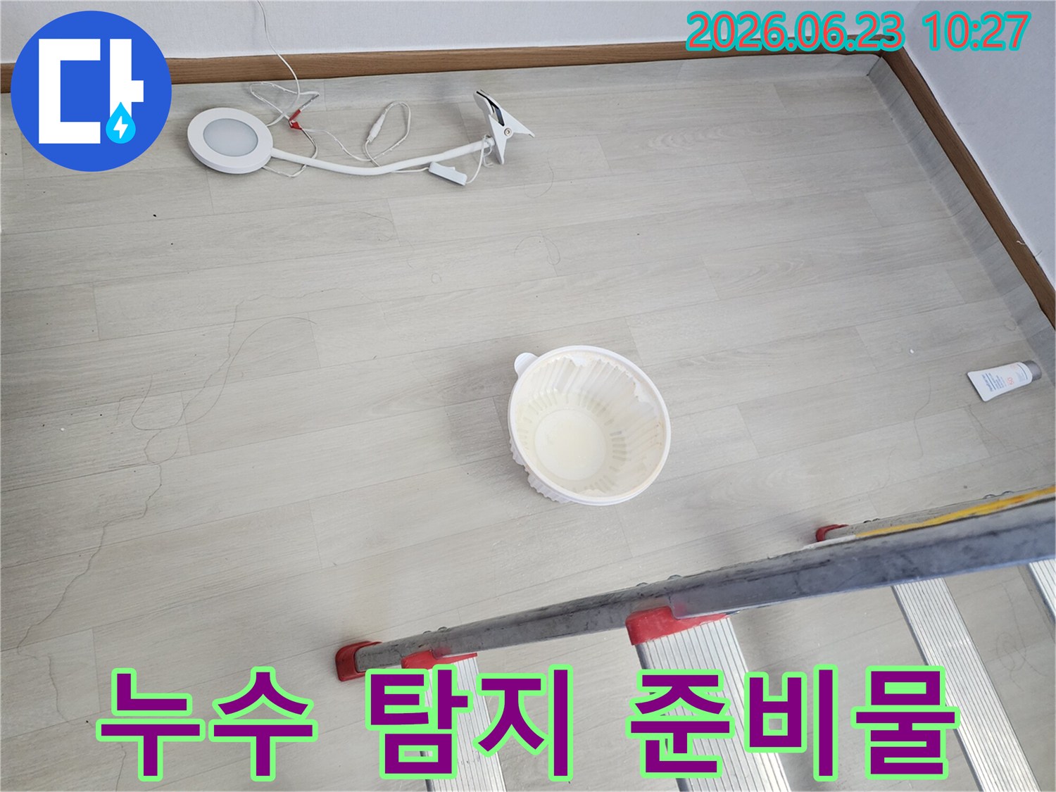 천장에서 떨어지는 물을 임시로 받는 그릇과-누수 지점 확인을 위한 사다리-정밀 탐지를 위한 조명 장비가 바닥에 놓여 있는-누수 공사 전 준비 모습입니다