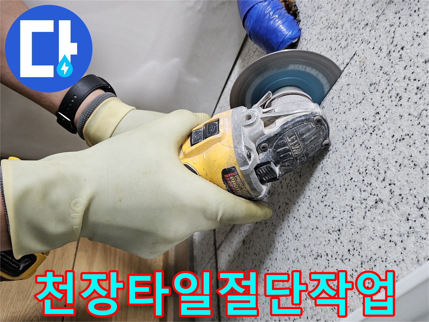 안전 장갑을 착용한 작업자가-그라인더로 천장 타일을-조심스럽게 절단하고 있습니다.